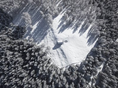 Winterurlaub im Stubaital mit Wow-Faktor ❄ Vogelperspektive eines verschneiten Waldes mit einer kleinen Hütte in der Mitte