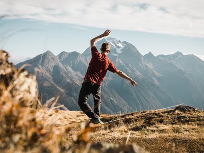 Unterkunft in Neustift im Stubaital: die beste Lage ⬤ Mann balanciert auf Slackline vor Bergkulisse