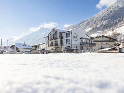 Deine Ferienwohnung in Neustift ✓ Schneebedeckte Häuser und Berge unter blauem Himmel in einem Dorf