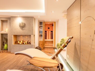 Your holiday apartment in Neustift ✓ Relaxation room with lounge chair, fireplace, and sauna in the background