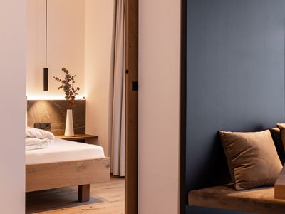 Deine Ferienwohnung in Neustift ✓ Modernes Schlafzimmer mit Holzmöbeln und Sitzbereich mit Kissen