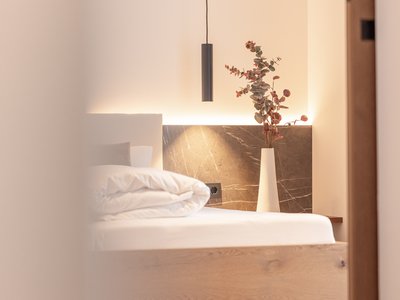 Your holiday apartment in Neustift ✓ Modern bedroom with wooden bed, vase with branches, and pendant light
