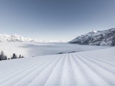 Unterkunft in Neustift im Stubaital: die beste Lage ⬤ Gepflegte Skipiste vor schneebedeckten Bergen und Nebel im Tal