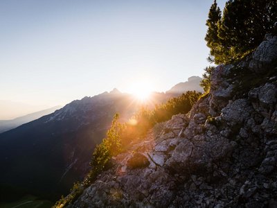 Beispielaufbau einer Unterseite Sonnenaufgang über felsigem Berg mit Bäumen im Vordergrund