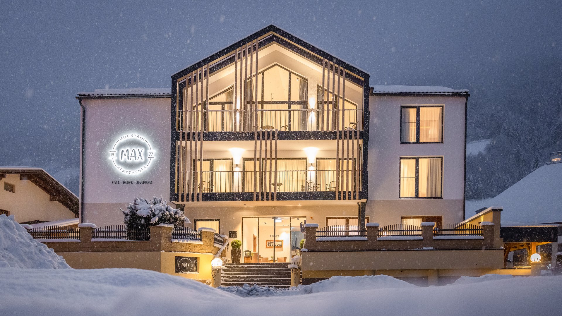 Ferienwohnung in Neustift im Stubaital mit Style ❥ Beleuchtetes Apartmenthaus im Winter mit Schnee und Schnee fällt abends