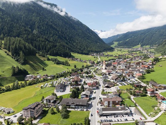 Beispielaufbau einer Unterseite Dorf in einem grünen Tal zwischen bewaldeten Bergen bei klarem Himmel