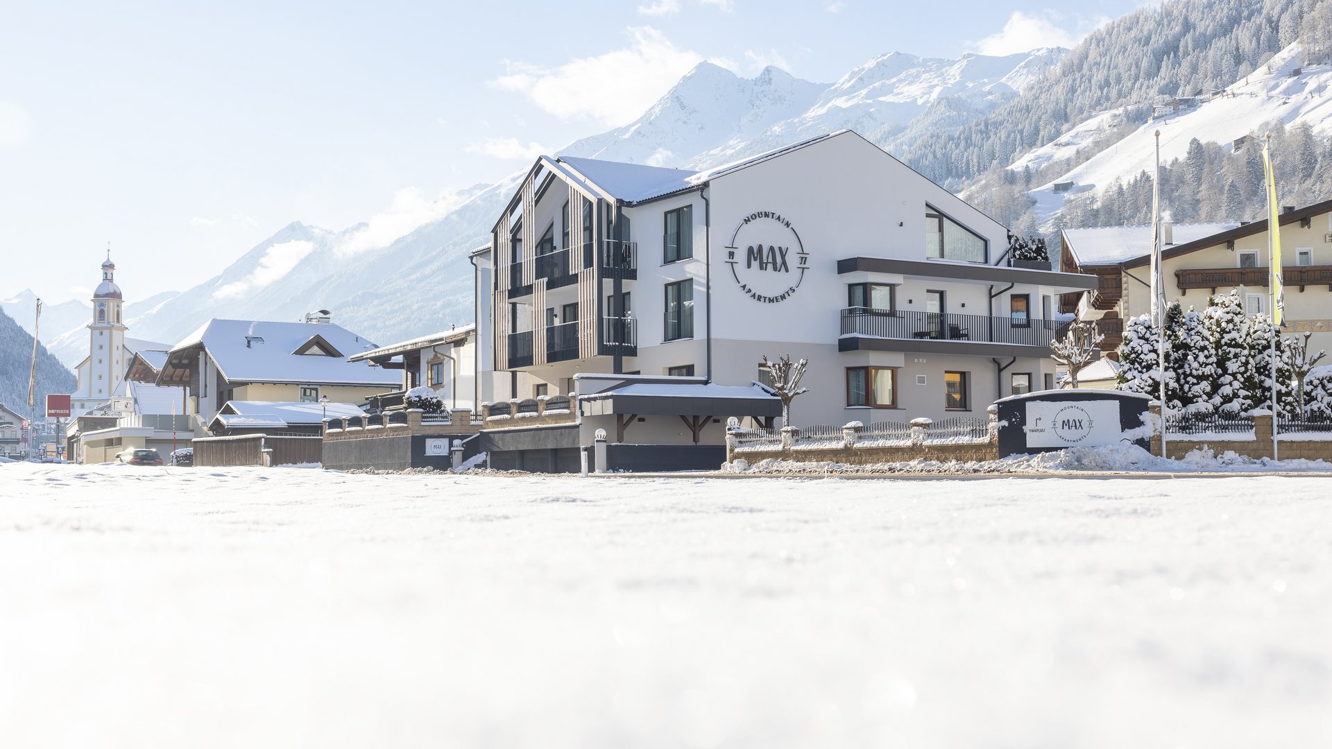 Schneebedecktes Hotelgebäude in einem Alpenort mit Bergen im Hintergrund