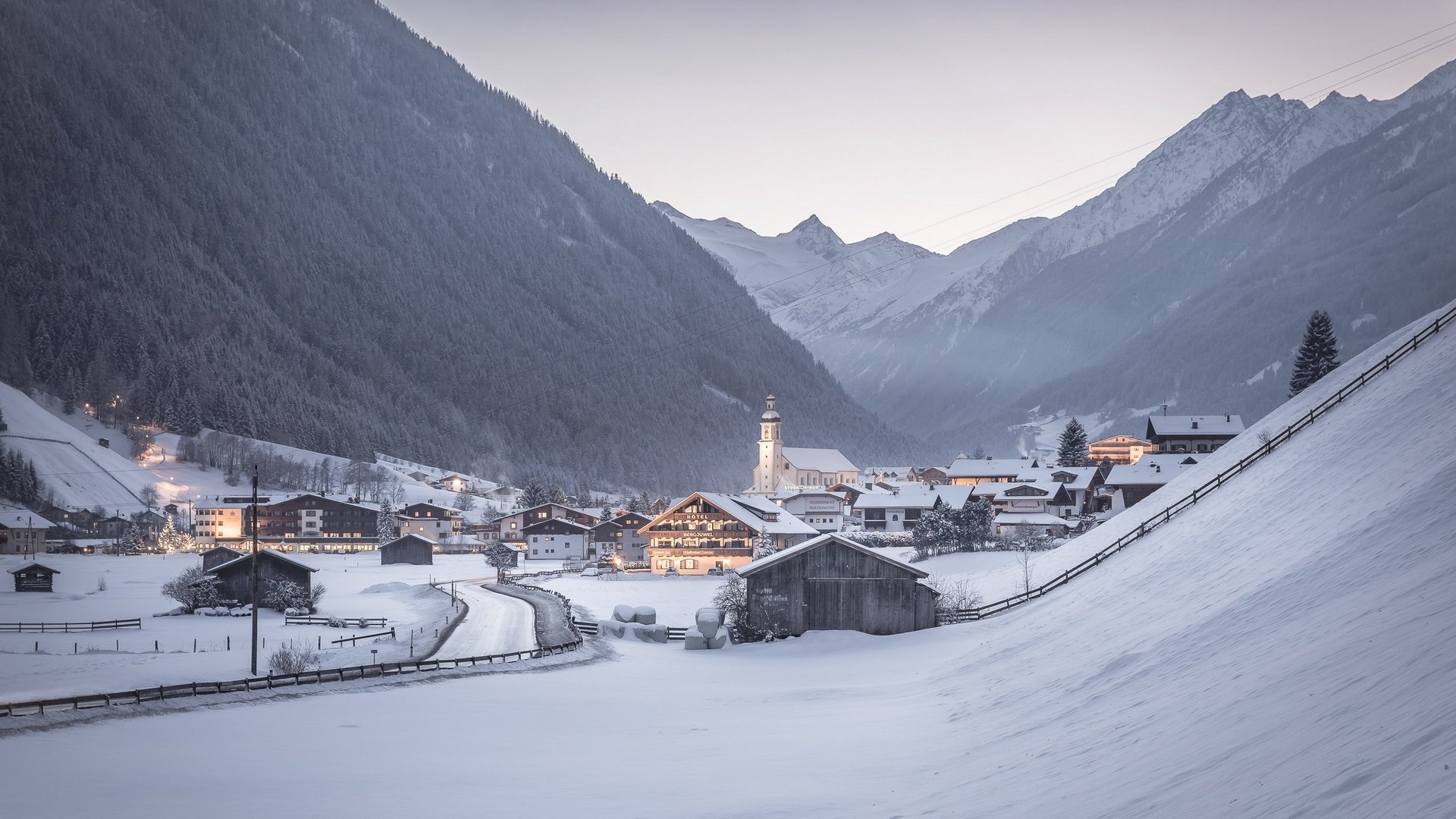 Winterurlaub im Stubaital mit Wow-Faktor ❄ Winterliches Dorf im Tal umgeben von schneebedeckten Bergen bei Dämmerung.