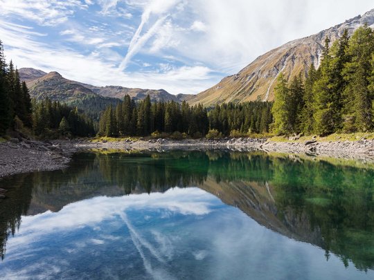 Beispielaufbau einer Unterseite Bergsee mit klarer Wasserreflexion von Bäumen und Bergen unter blauem Himmel